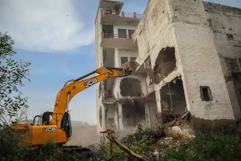 A bulldozer is demolishing a Muslim property in India.