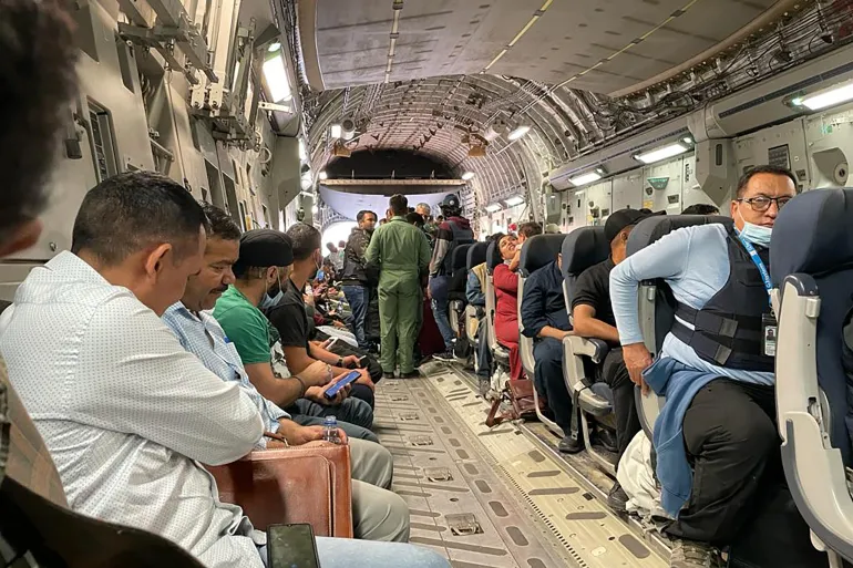 Indian nationals sit on board an Indian military aircraft at the airport in Kabul [AFP]