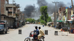 Bannu Attack: Men on a bike watch smoke rise after militants' suicide squad tried to storm an army cantonment in Bannu on July 15, 2024. (AFP)