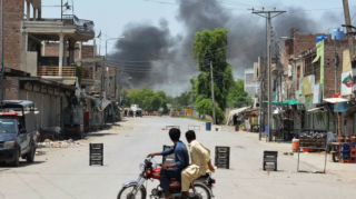 Bannu Attack: Men on a bike watch smoke rise after militants' suicide squad tried to storm an army cantonment in Bannu on July 15, 2024. (AFP)