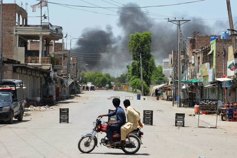 Bannu Attack: Men on a bike watch smoke rise after militants' suicide squad tried to storm an army cantonment in Bannu on July 15, 2024. (AFP)