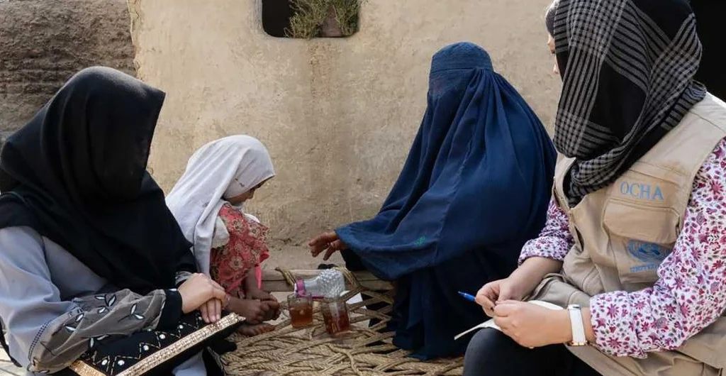 A staff member with the UN Office for the Coordination of Humanitarian Affairs (OCHA) speaks with displaced women in the eastern province of Nangahar in Afghanistan.