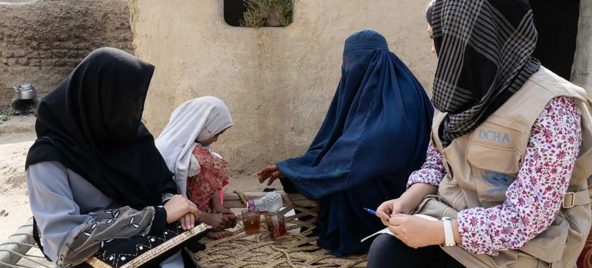 A staff member with the UN Office for the Coordination of Humanitarian Affairs (OCHA) speaks with displaced women in the eastern province of Nangahar in Afghanistan.