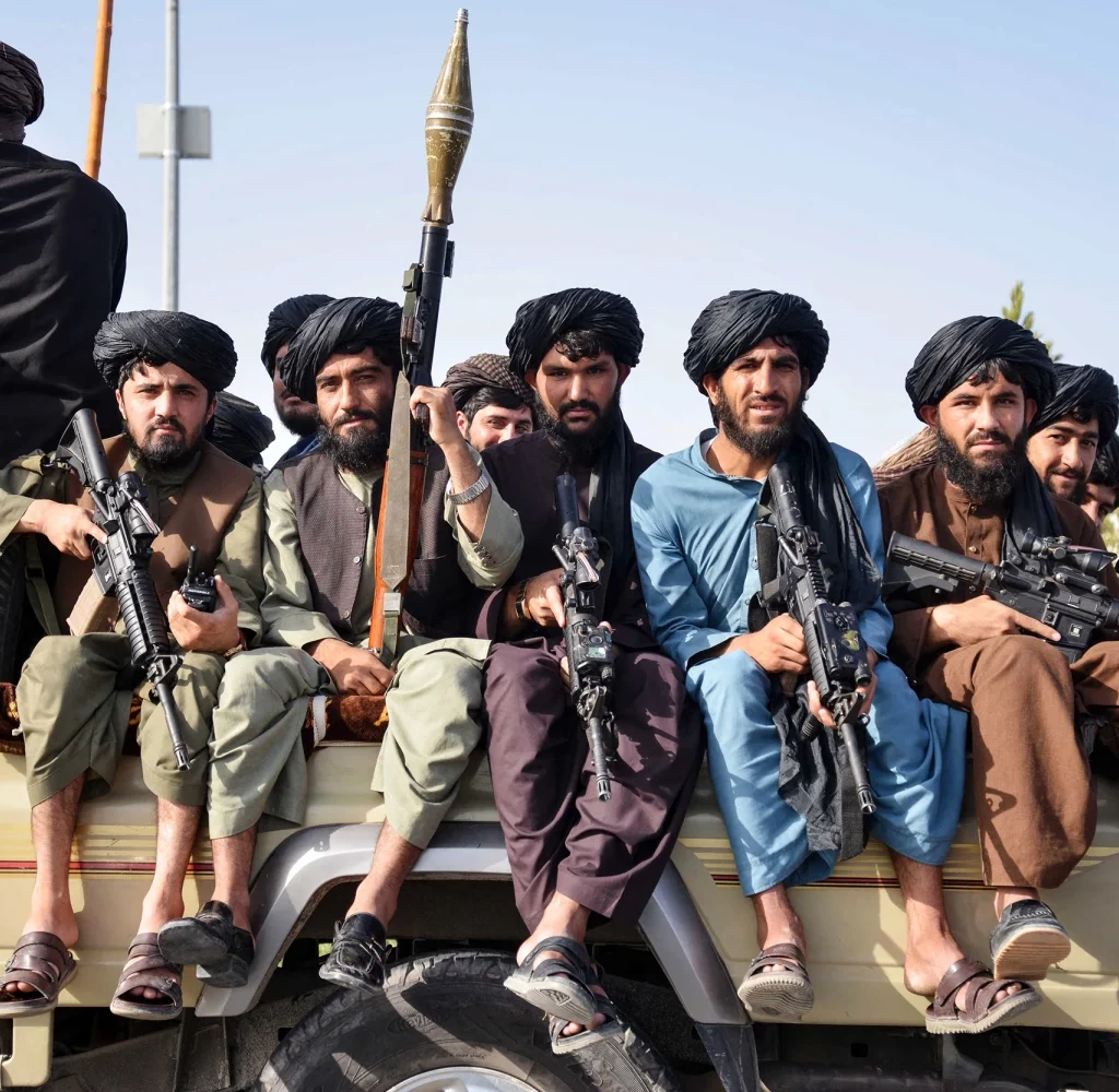 Taliban security personnel sit atop a military vehicle during a parade to celebrate the third anniversary of Taliban's takeover of the country in Kandahar