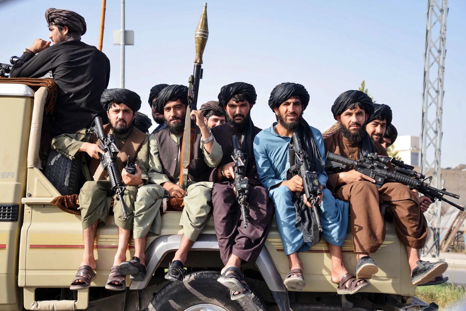 Taliban security personnel sit atop a military vehicle during a parade to celebrate the third anniversary of Taliban's takeover of the country in Kandahar