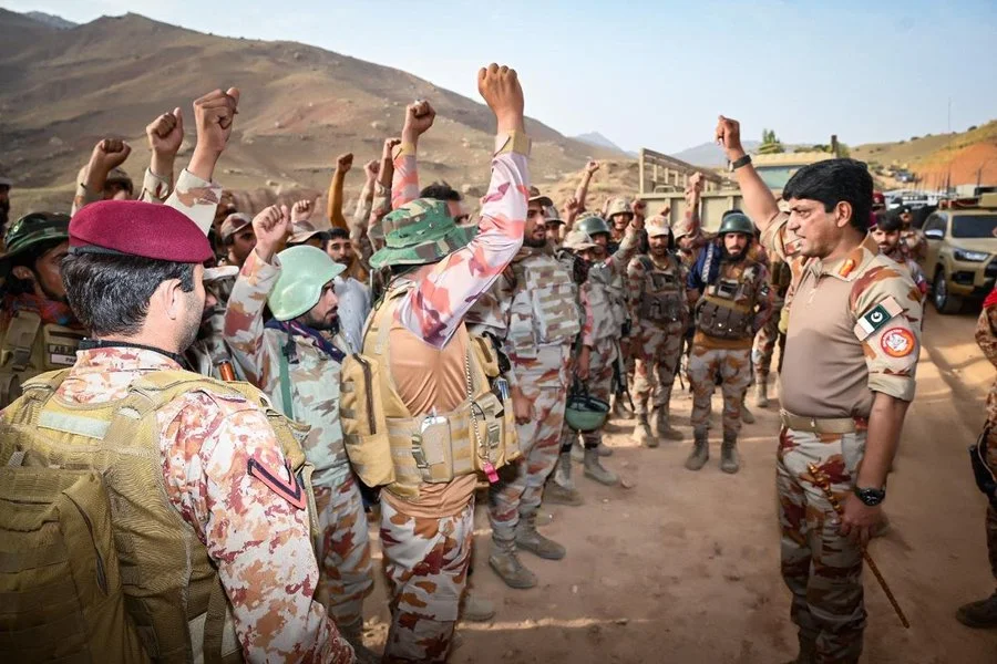 Pakistan Army personnel gathered during Operation Shabaan in Balochistan, with soldiers raising their fists as a senior officer addresses the formation in a mountainous area.