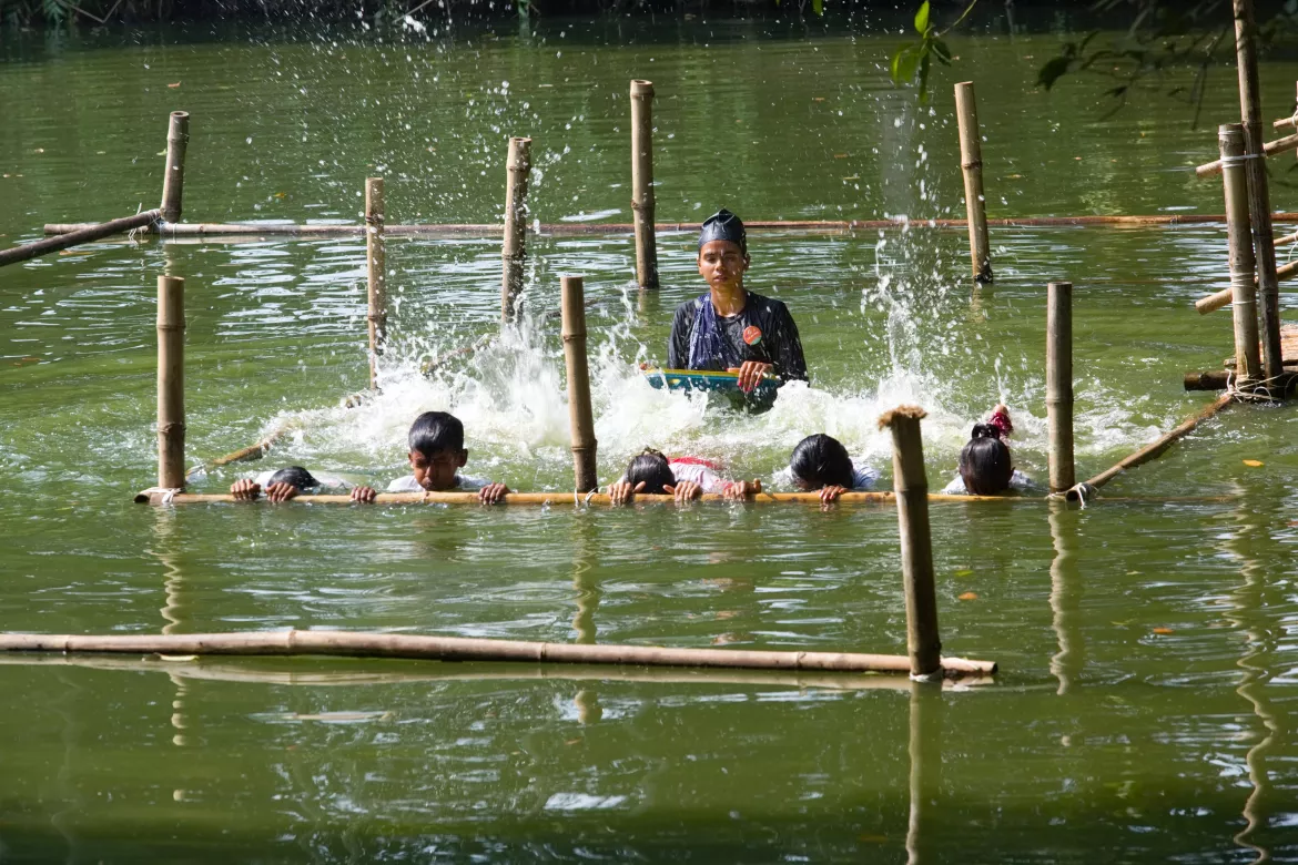 Mim Akter, a prominent young Bangladeshi community swimming instructor, in water with her students, showing them breathing, floating, and rescuing techniques. [Image Credits: UNICEF Bangladesh].