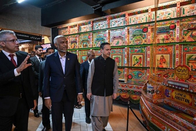 The President walks past a brightly painted display of Pakistani truck art at the Lok Virsa museum.