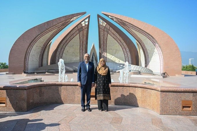 The President and First Lady stand together in front of the petal-shaped granite wings of the Pakistan Monument.