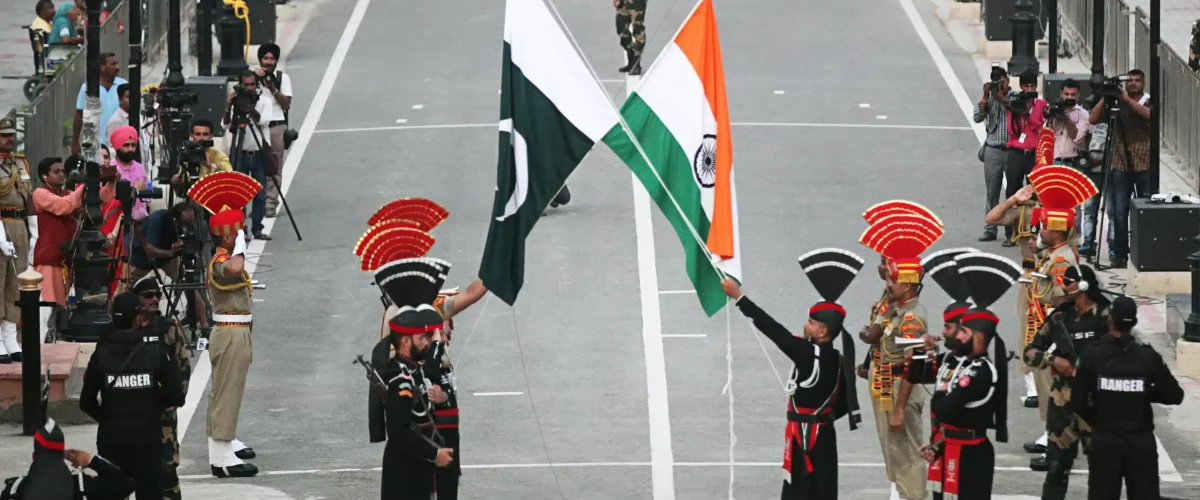 Pakistan-India ties: Pakistani Rangers, clad in black uniforms, and Indian Border Security Force (BSF) officers lower their national flags during a parade at the Pakistan-India joint check-post at Wagah border, near Lahore, Pakistan, on August 14, 2019. (Source: REUTERS/Mohsin Raza)